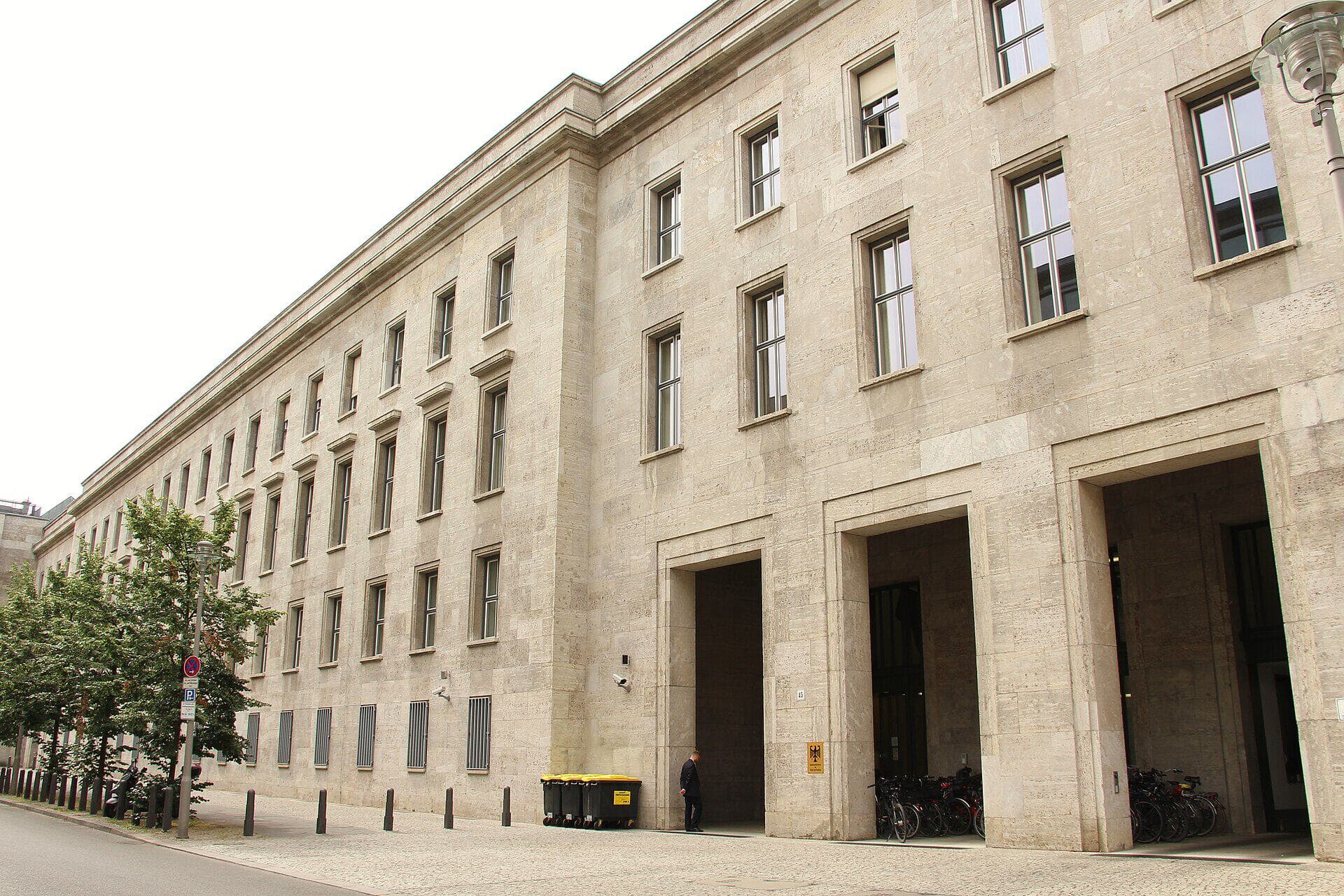 Muschelkalk-Fassade des BMAS-Dienstsitzes in Berlin-Mitte (Mauerstraße-Seite des Gebäudekomplexes Wilhelmstraße 49) mit drei großen Eingangsportalen und Bundesadler-Schild.