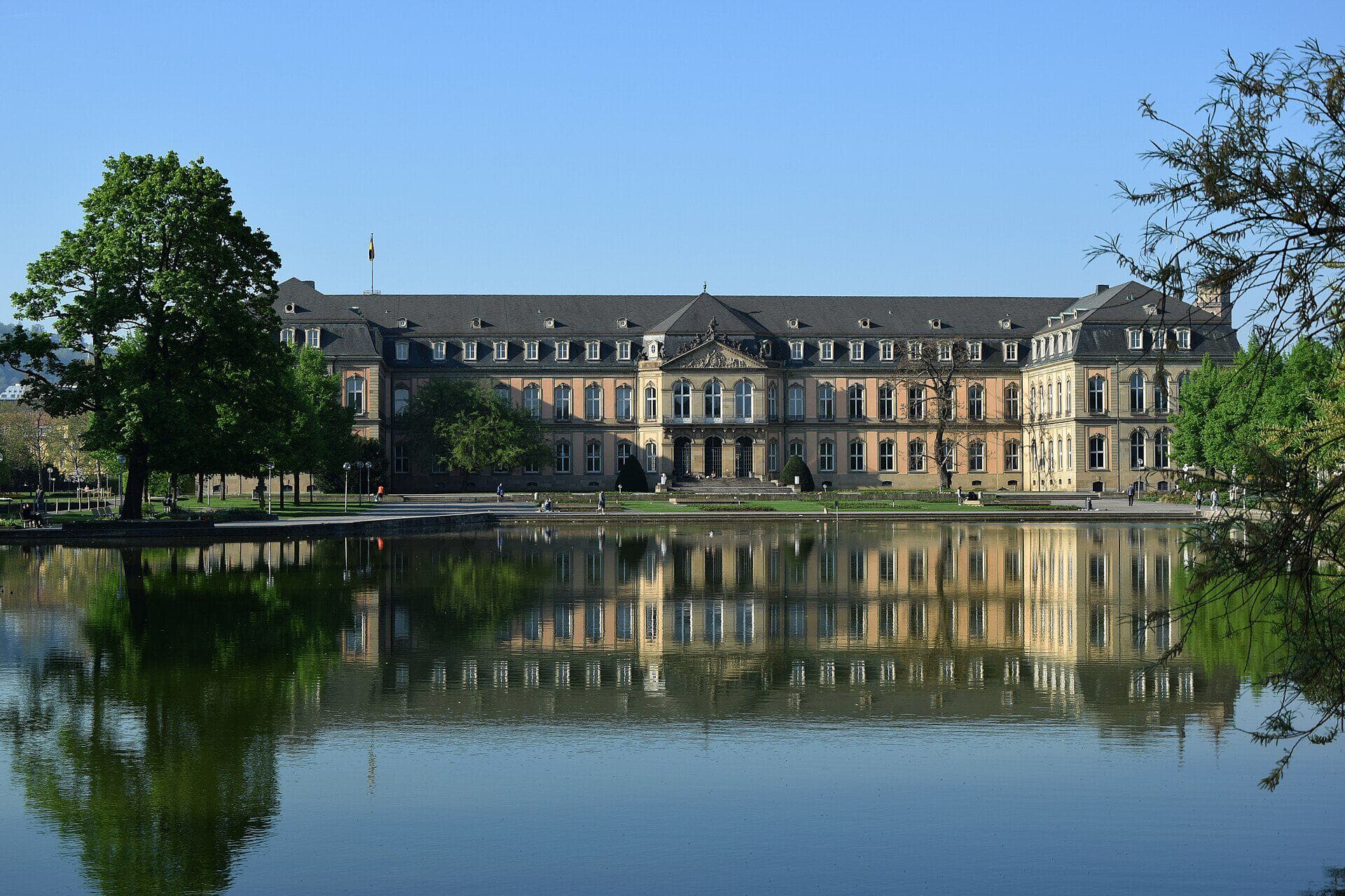 Gartenflügel des Neuen Schlosses in Stuttgart (Sitz von Finanz- und Innenministerium) über den Eckensee im Oberen Schlossgarten gesehen, bei blauem Himmel.