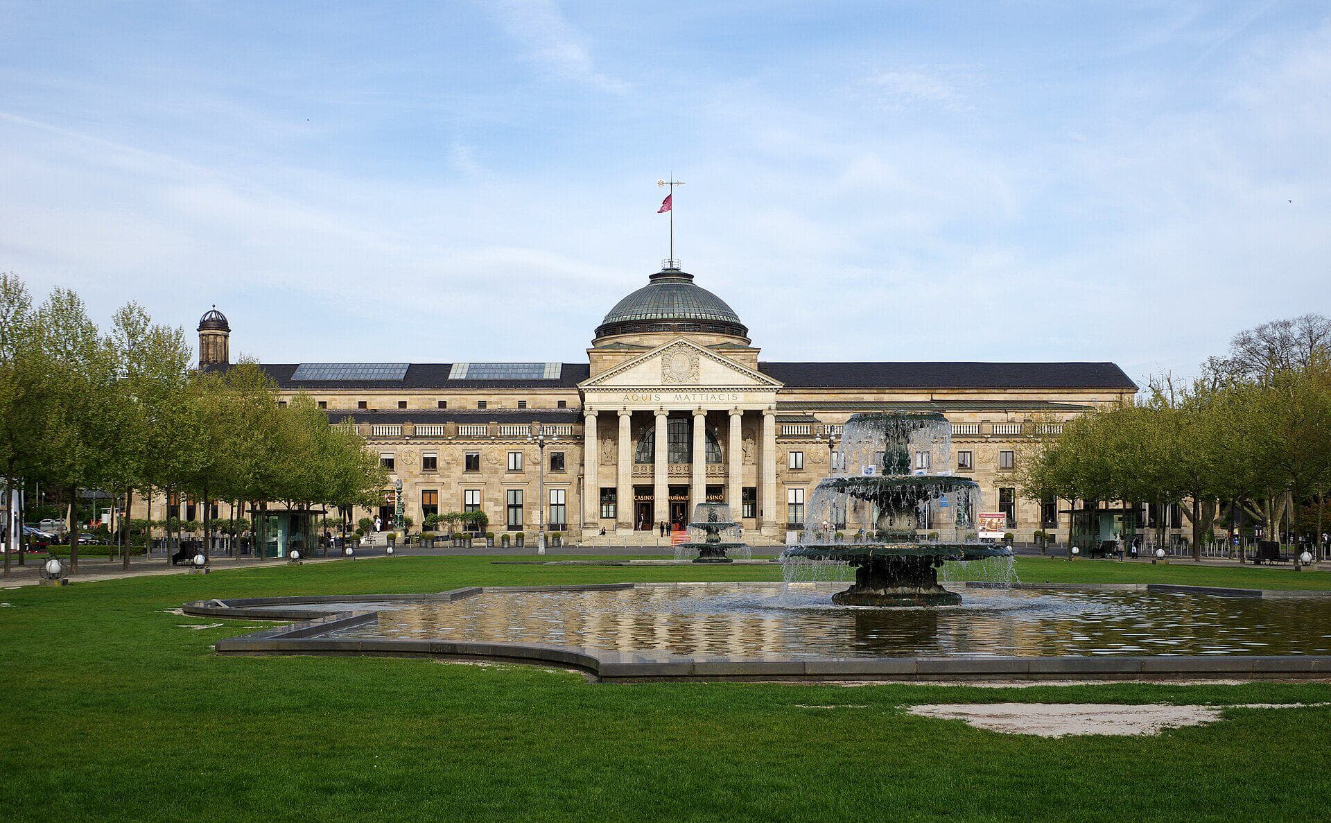 Das Kurhaus Wiesbaden mit Säulenportikus und Kuppel, davor das Bowling Green mit Springbrunnen.