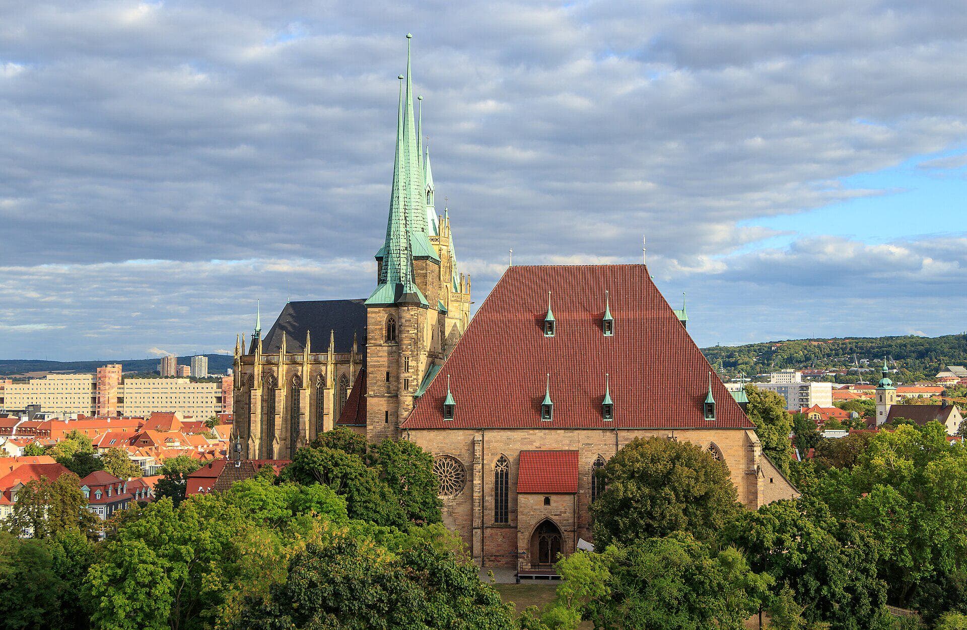 Erfurter Mariendom und Severikirche, vom Petersberg aus gesehen, bei Tageslicht über den Bäumen und Dächern der Altstadt.